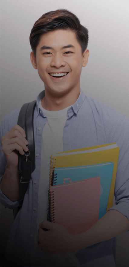 A man with dark hair stands against a white background and holds three multi-colored notebooks with a backpack slung over one shoulder. He is wearing a white t-shirt under an open, light-blue collared shirt and smiling while looking directly at the camera.