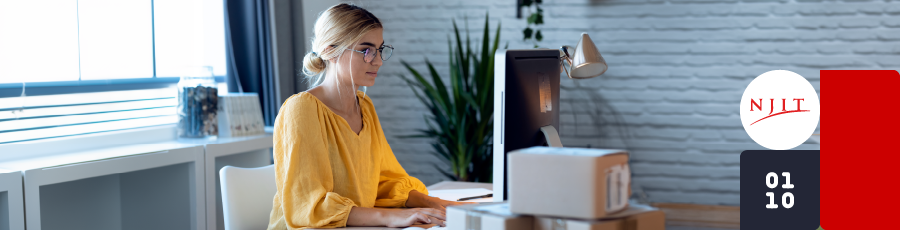 Person working at a desk with two monitors, a laptop, and NJIT logo in an office.

